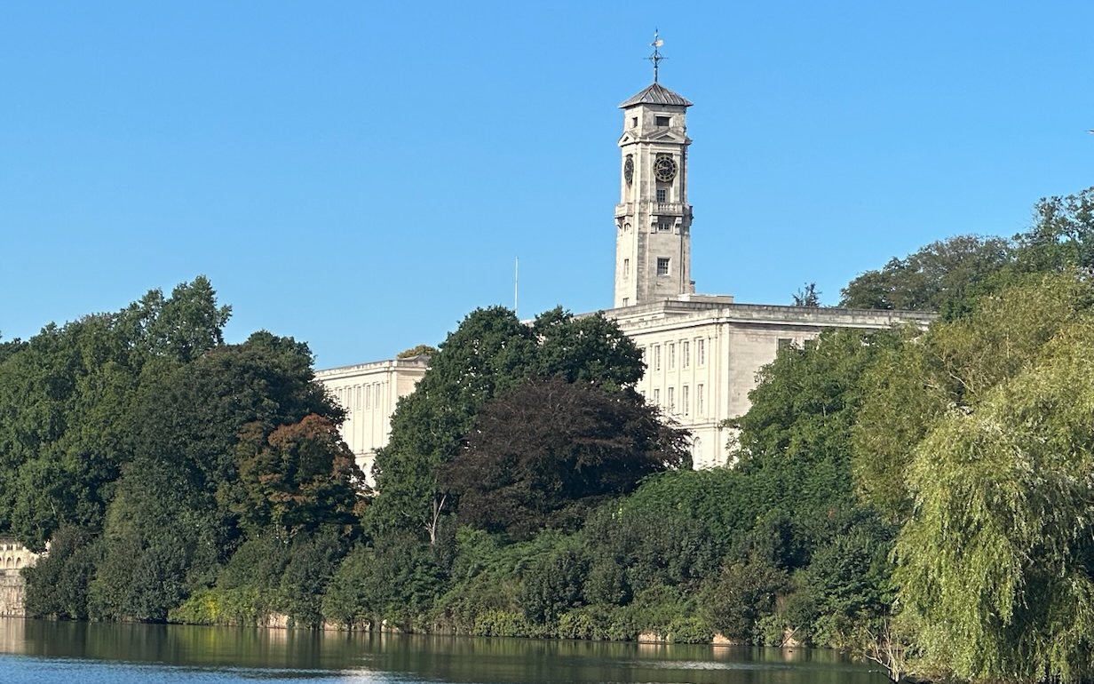The clock tower of the Trent Building at the University of Nottingham, above the trees by the lake.